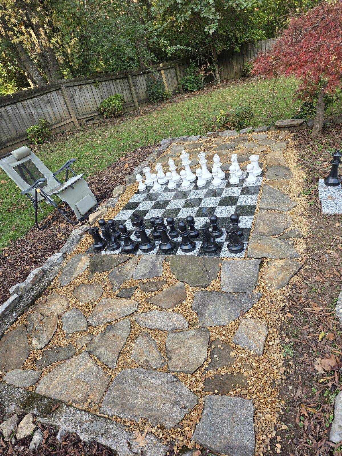 Giant outdoor chessboard set into a flagstone and gravel patio